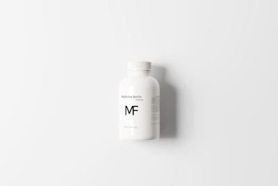 A white plastic bottle positioned centrally against a white background, featuring the label 'Medicine Bottle Mockup MF' in simple black text. The bottle has a smooth surface with a screw cap and additional small print details on the label.