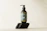 Close-up of a sleek silver and black Aurumvetta product bottle resting on a smooth stone surface.