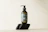 Close-up of a sleek silver and black Aurumvetta product bottle resting on a smooth stone surface.
