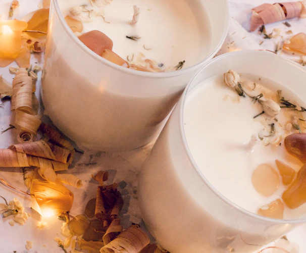 Cozy candlelit scene with soft glowing wax melts on a wooden tray surrounded by dried flowers.