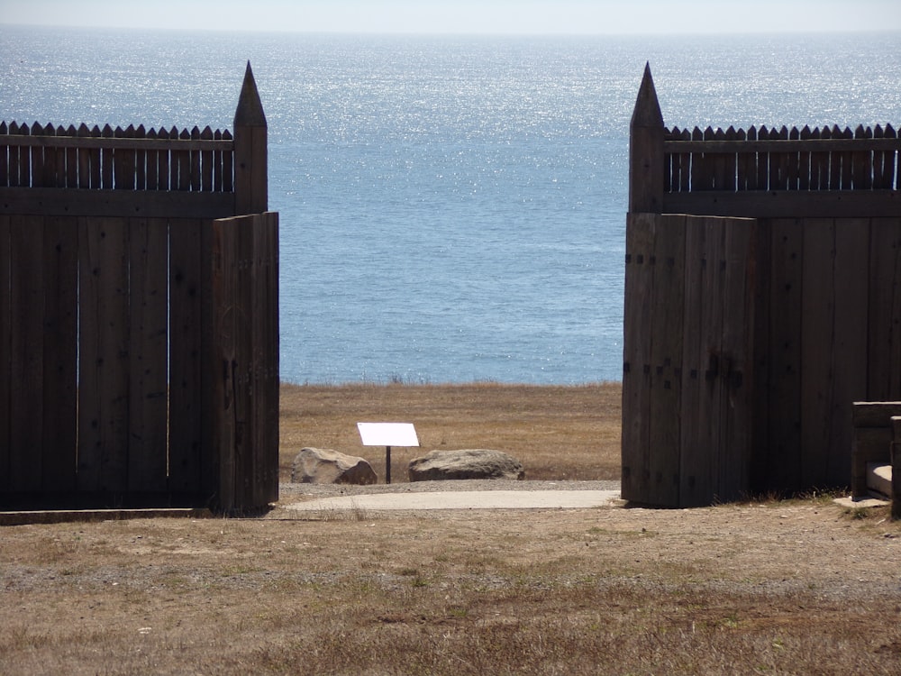 an open gate with a bench in front of a body of water
