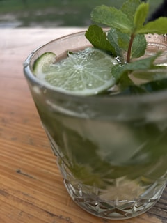 A vibrant glass of iced hibiscus tea garnished with a slice of lime and mint leaves on a sunny patio.