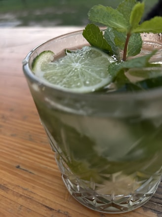 A sleek glass tumbler filled with iced tea and mint leaves on a sunny patio.