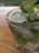 Close-up of a refreshing glass of Herbafizz with fresh herbs on a wooden table outdoors.