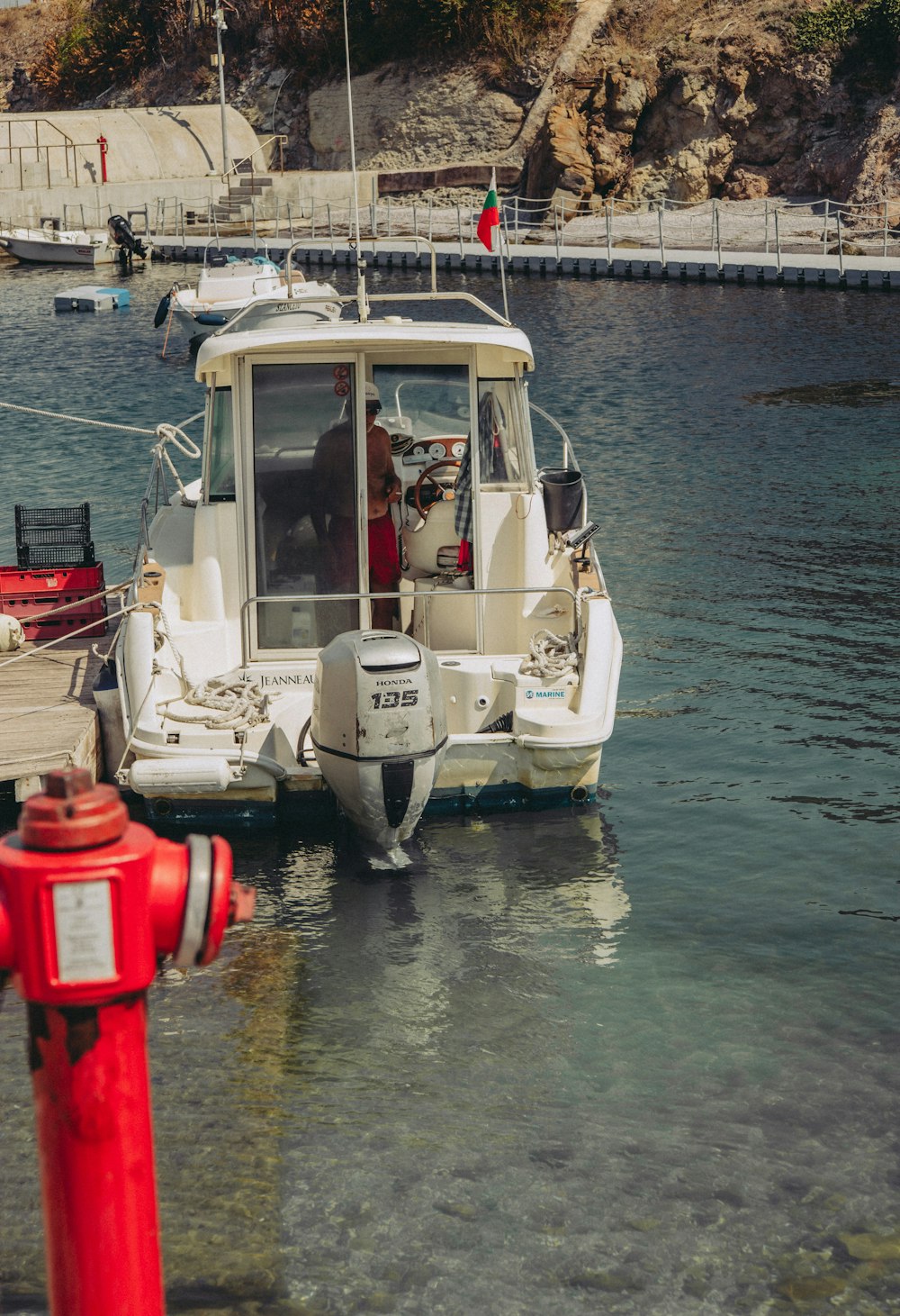 a boat is docked at a dock with a red fire hydrant