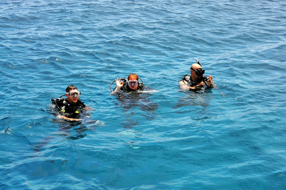three people in the water wearing scuba gear