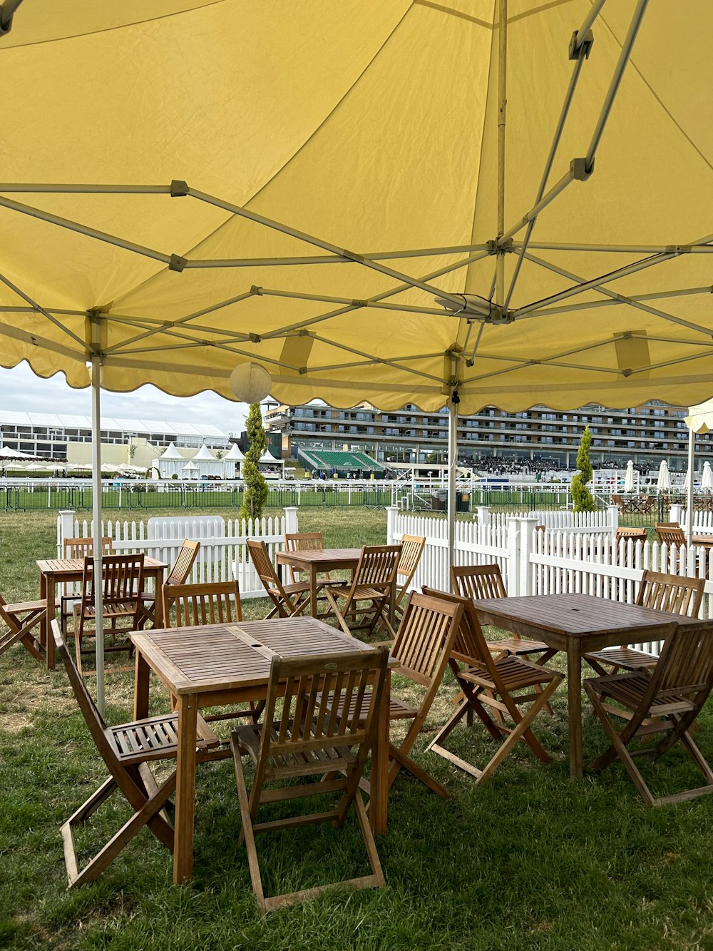 a group of wooden tables and chairs under a yellow umbrella