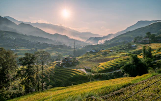 the sun is setting over a green valley