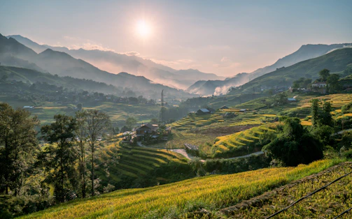 A serene mountain landscape with terraced rice fields glowing at sunset.