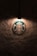 A logo featuring a mermaid with two tails is illuminated by a single overhead light against a textured, dark wall.
