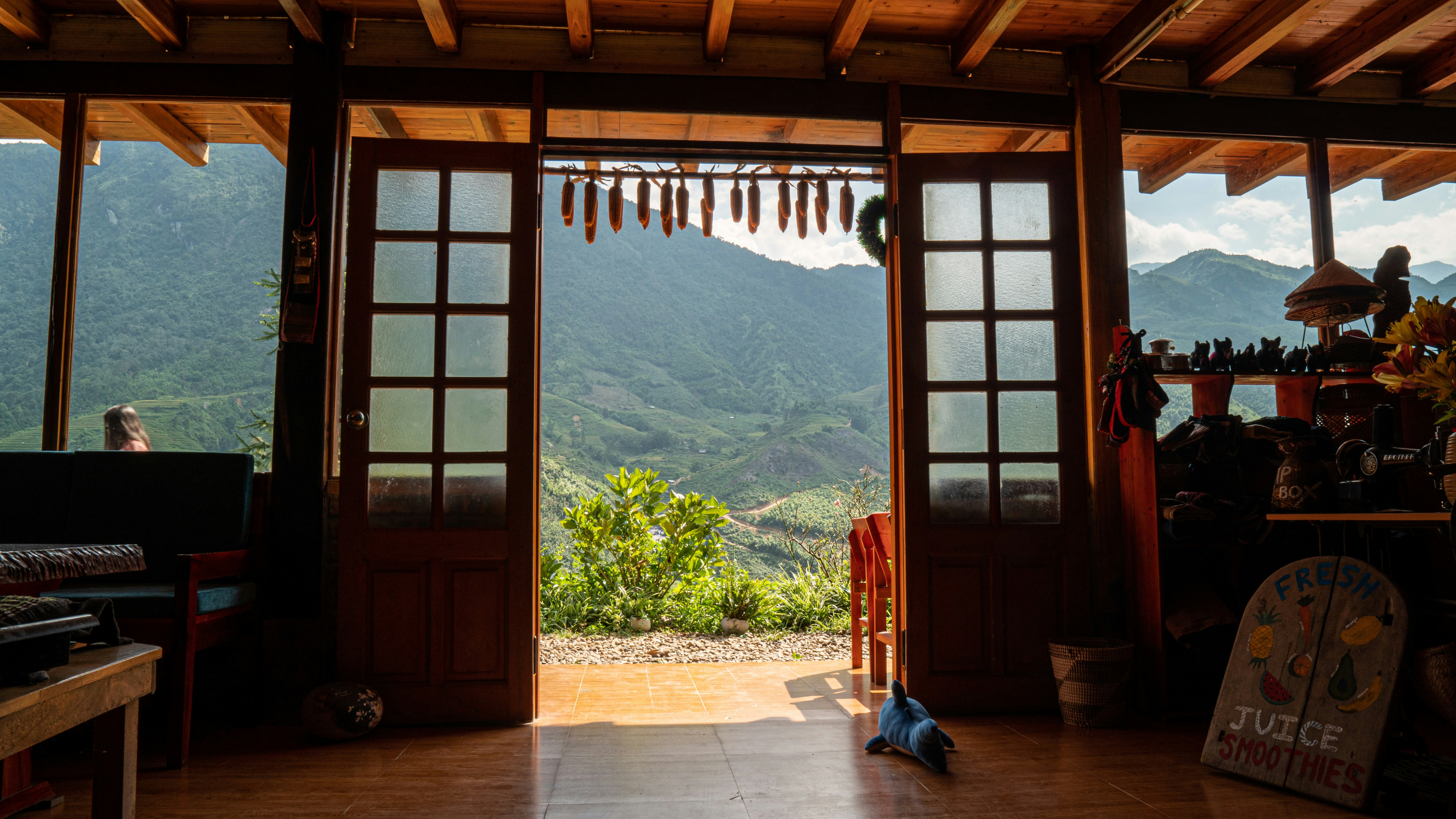 a room with open doors and mountains in the background, 