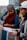 Two women are engaged in a focused discussion, holding papers in their hands. One woman wears a colorful headscarf and a maroon vest over a blue top, while the other wears a light-colored cap and a dark hoodie. They appear to be outdoors with a natural landscape in the background.