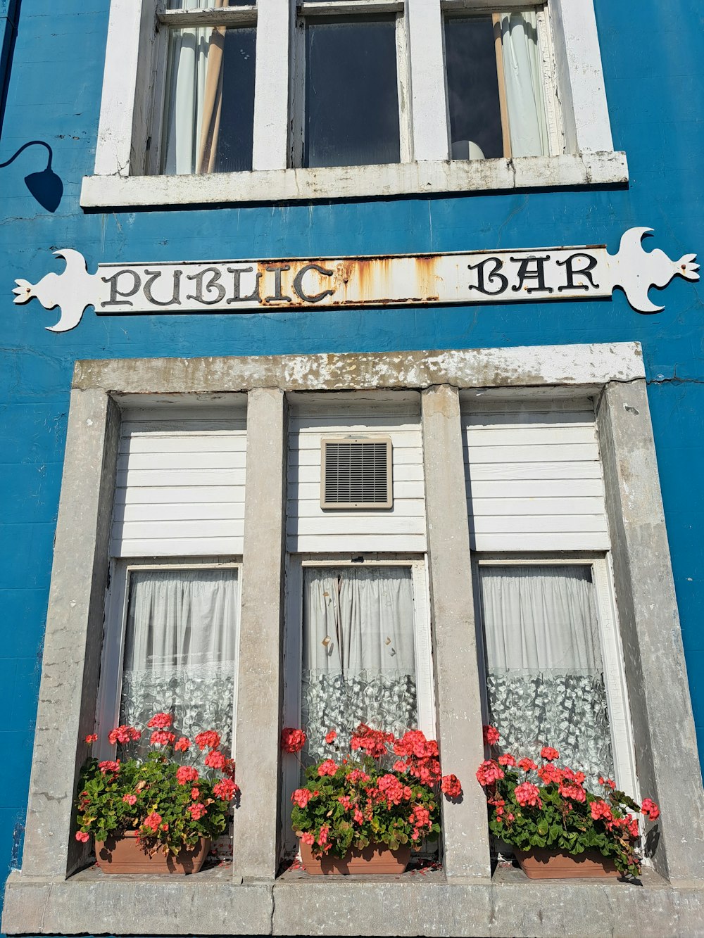 a blue building with windows and flowers in the windows