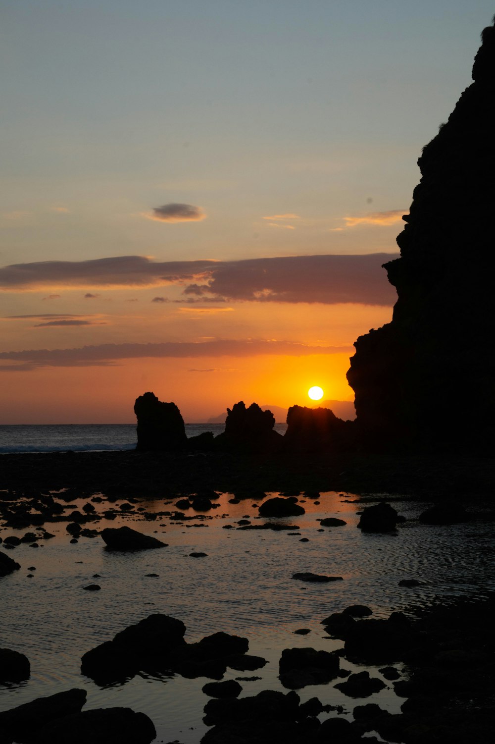 the sun is setting over a rocky beach