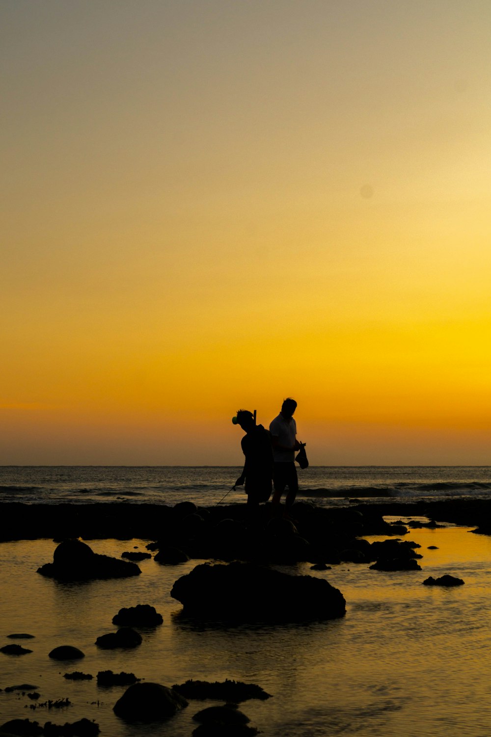 a couple of people riding horses across a body of water