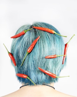 a woman with blue hair and red chilis on her head