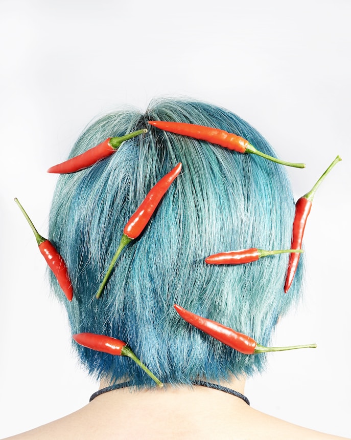 a woman with blue hair and red chilis on her head