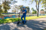 A rider cruising along a sunlit city street on a shiny ridenest electric scooter.