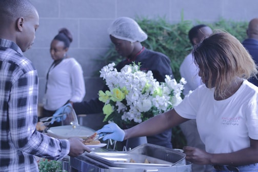 Warm staff serving guests with smiles at a home party buffet