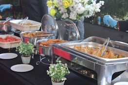 Guests enjoying a catered event outdoors with warm lighting and Indian cuisine served buffet-style.