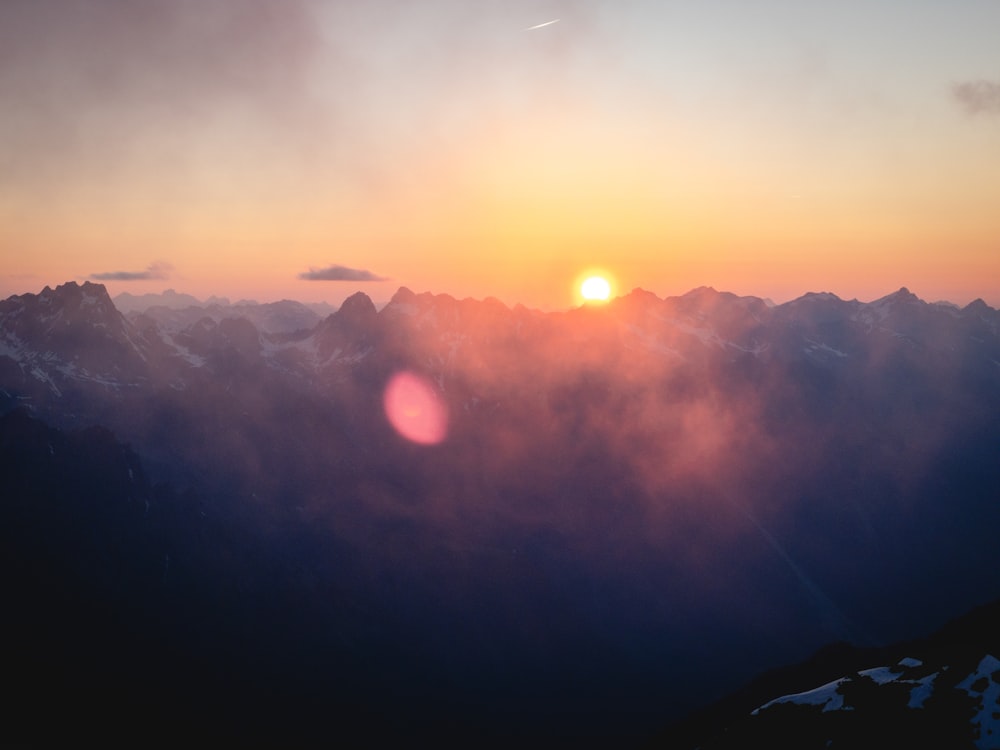 the sun is setting over a mountain range