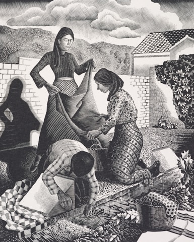 Three figures engaged in communal work outdoors. A woman in a long dress holds a large piece of fabric while another woman kneels, assisting with the fabric. A third person, bending over, works on the ground, surrounded by a basket and patterned textiles. The background shows trees, hills, a house, and a cloudy sky, creating a rural and serene setting.