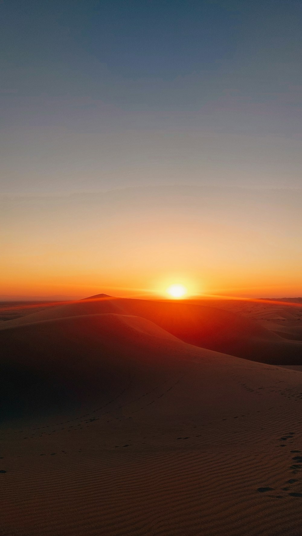 the sun is setting over the sand dunes