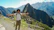 Smiling traveler standing in front of Machu Picchu ruins during sunrise.