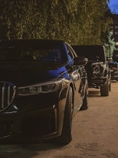 A row of elegant black luxury cars parked under soft golden lighting.