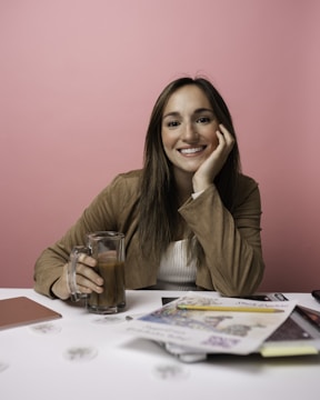 a woman sitting at a table with a glass of coffee