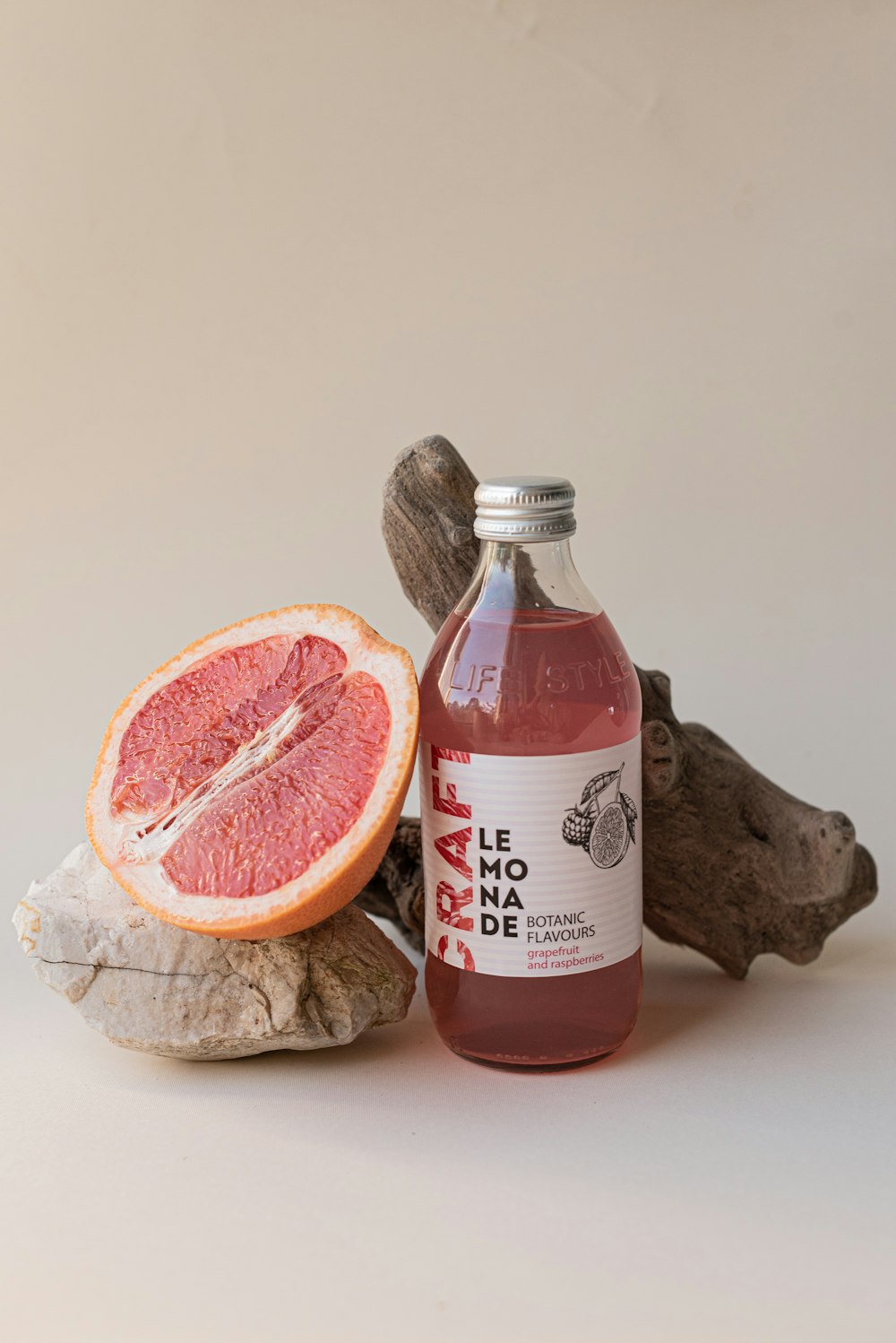 a bottle of blood orange juice next to a grapefruit