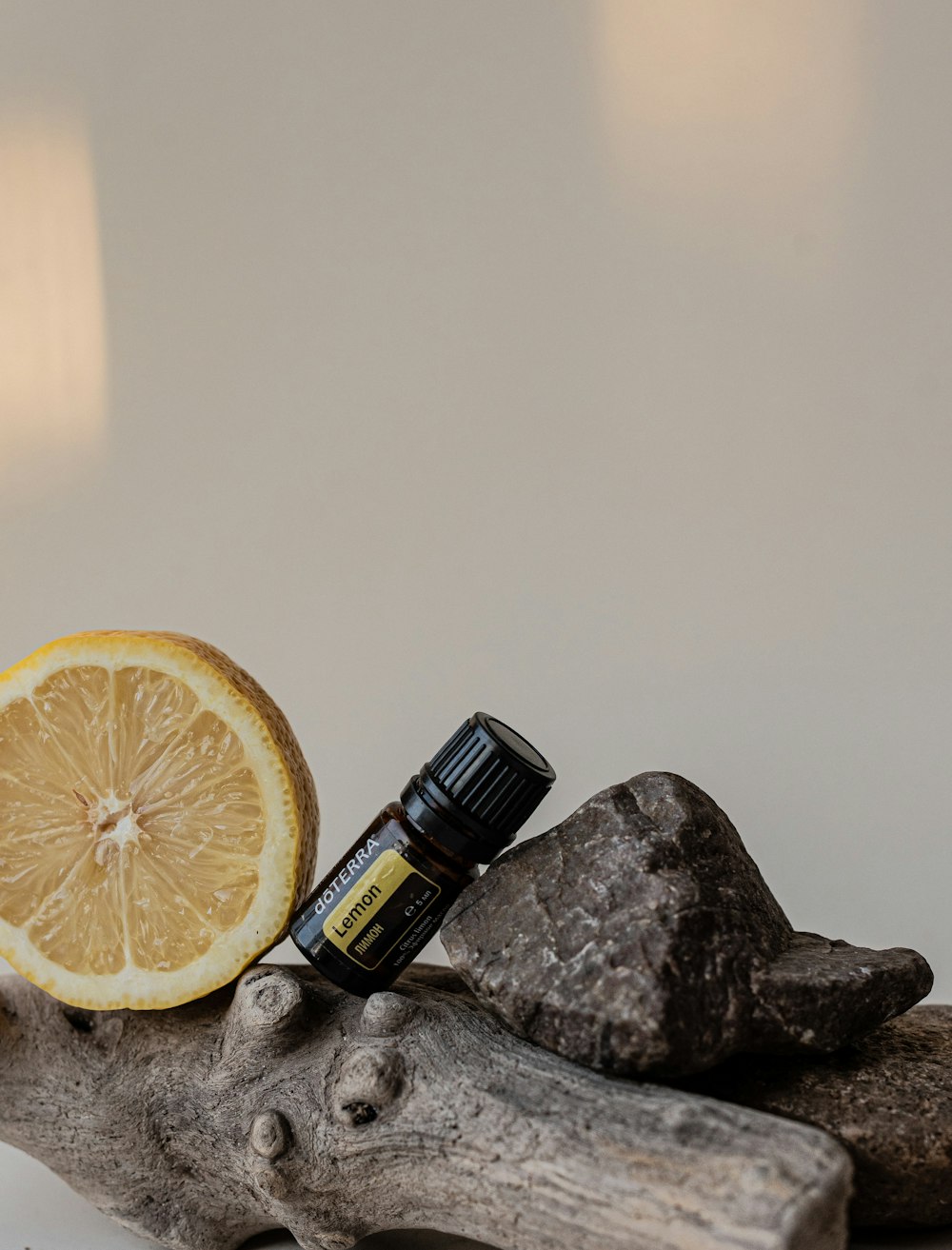 a lemon and an essential oil sitting on a piece of driftwood