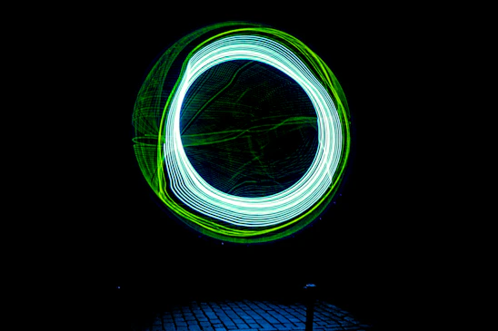 A sleek cyberpunk-inspired LED poi glowing with electric blue and neon green trails against a dark background.
