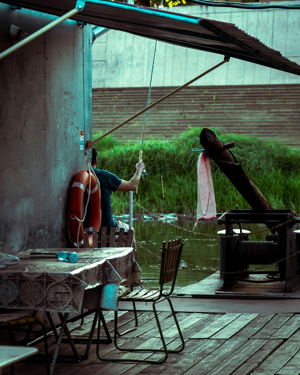 a man is standing on a dock holding a fishing rod