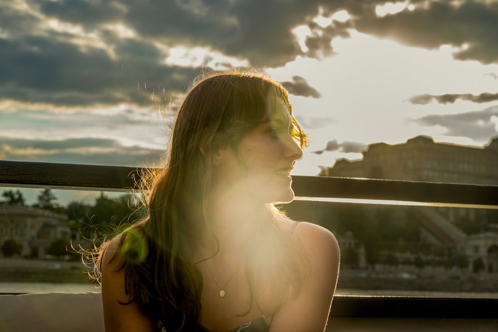 a woman sitting on a bench in front of the sun