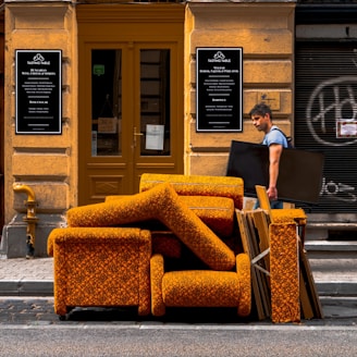 a man walking past a pile of orange couches