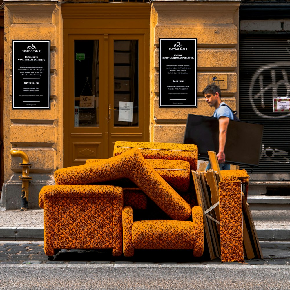 a man walking past a pile of orange couches