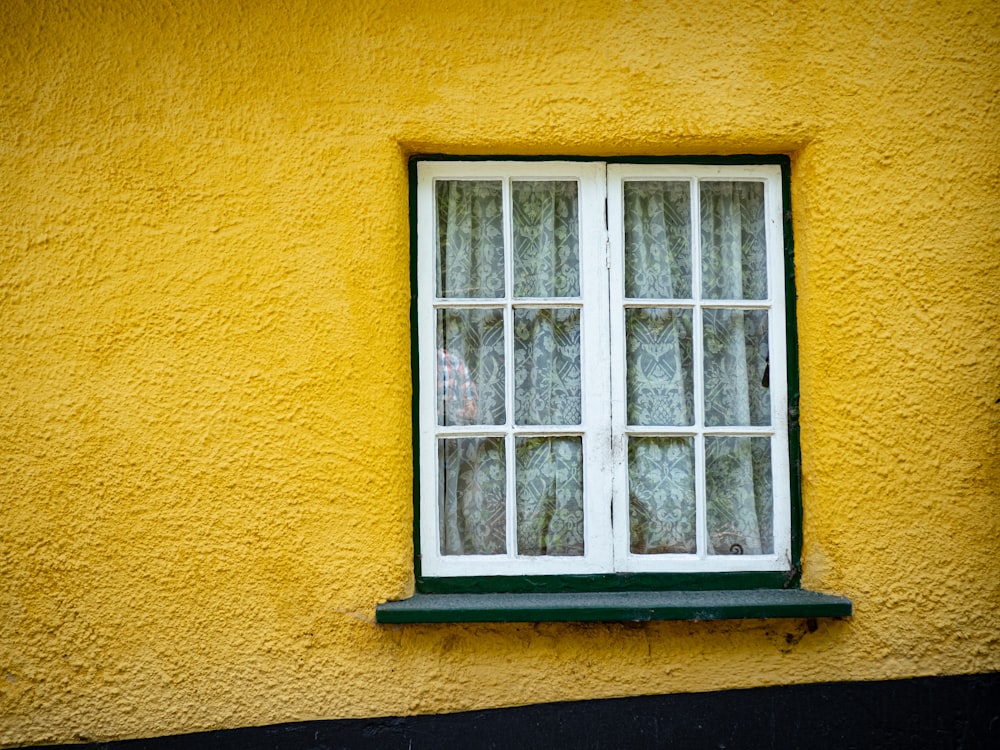 a yellow building with a white window and green trim