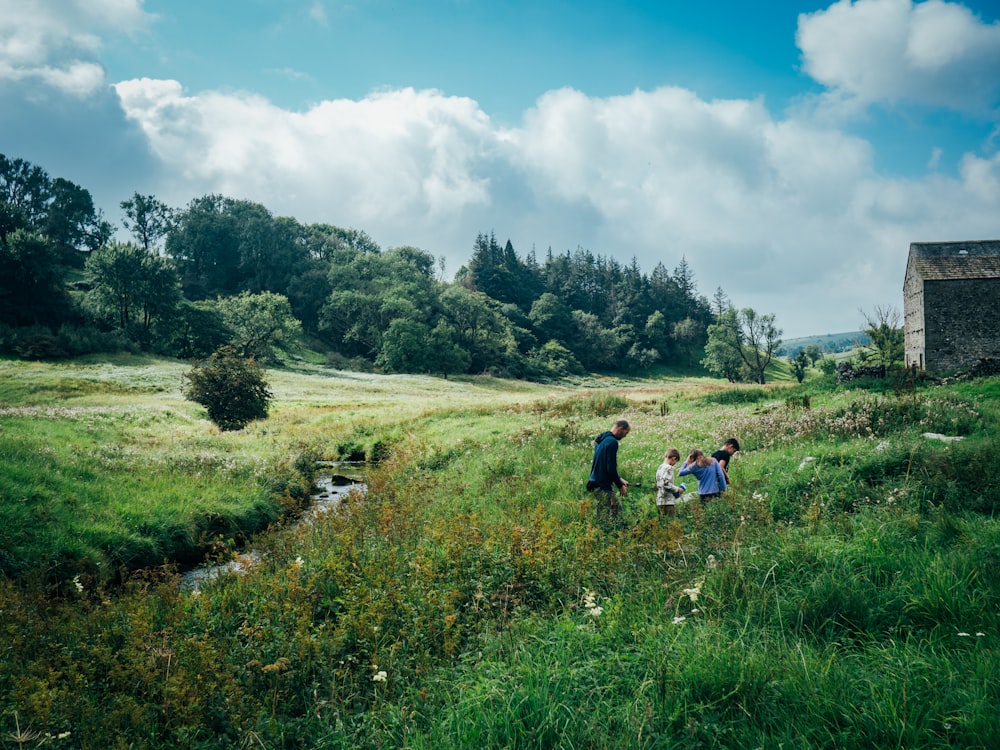 a group of people walking across a lush green field