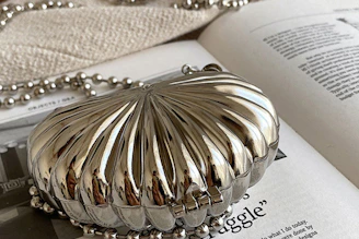 A delicate nude clutch placed on a marble surface with soft shadows highlighting its sleek design.