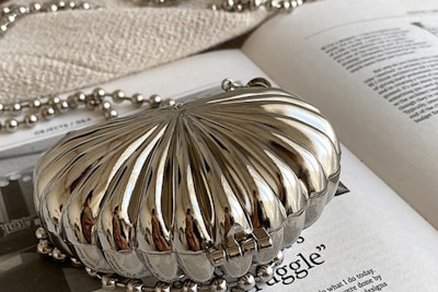 An elegant clutch bag placed on a marble surface with delicate stitching details visible.