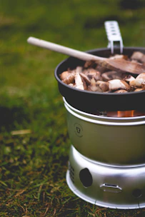 A portable camping stove with a pot simmering over the flame, surrounded by fresh ingredients.