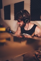 Musician playing guitar with headphones on, immersed in the recording process.