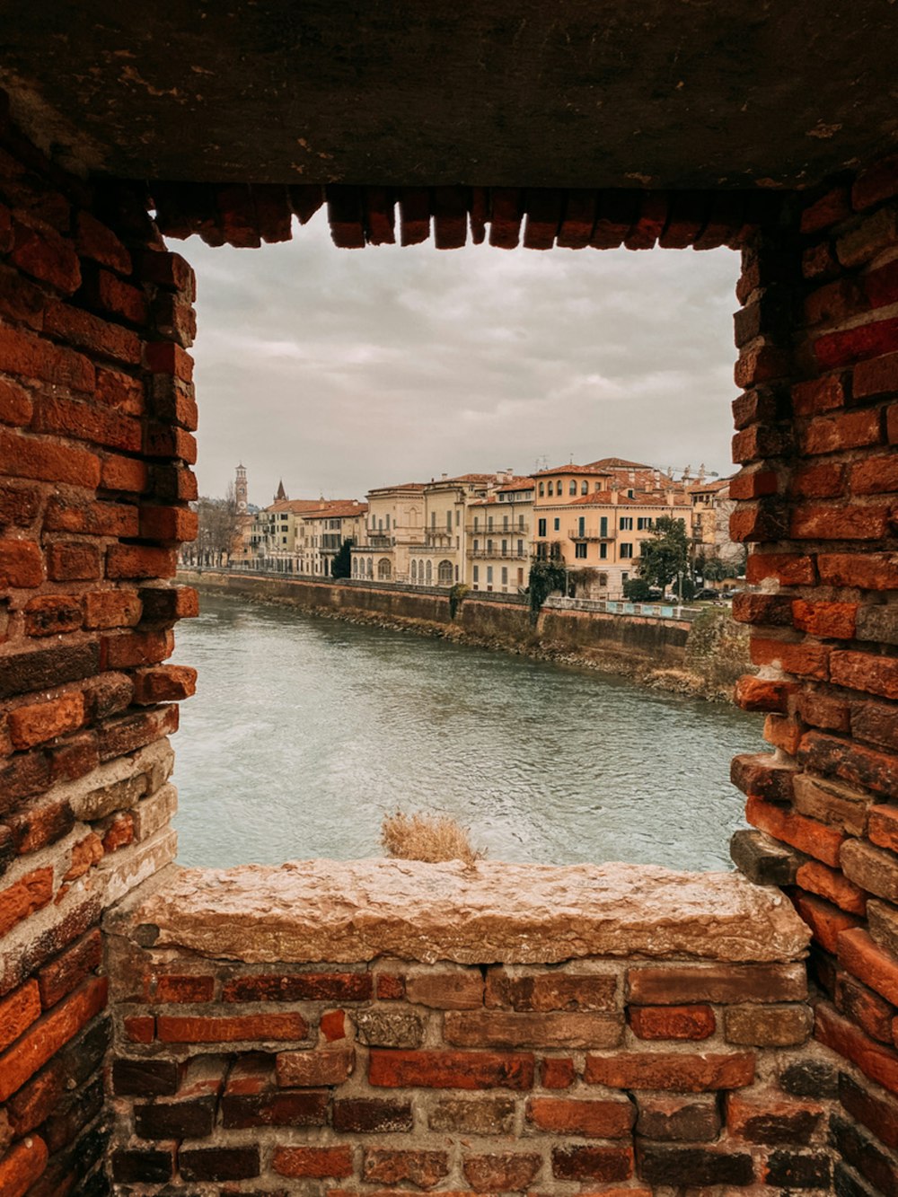a view of a river through a hole in a brick wall
