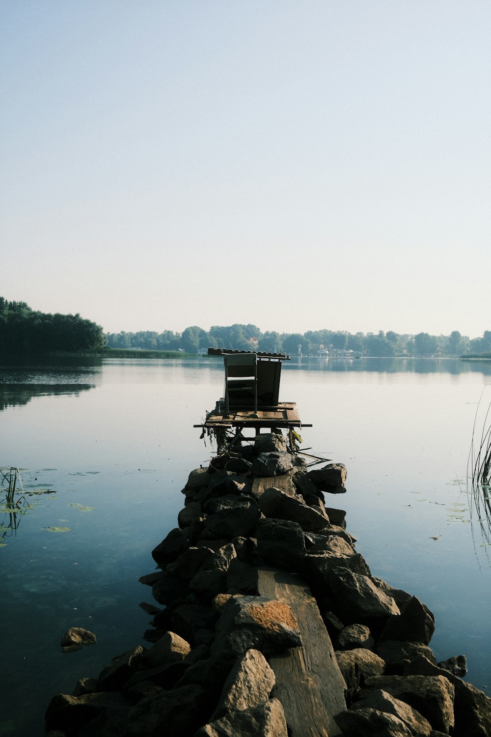 a chair sitting on top of a wooden dock next to a body of water