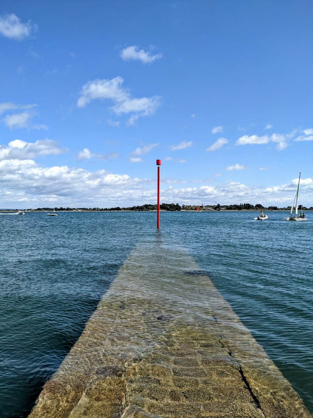 a long dock with a red pole sticking out of the water