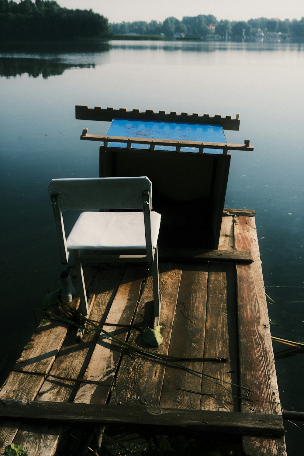 a chair sitting on top of a wooden dock next to a body of water