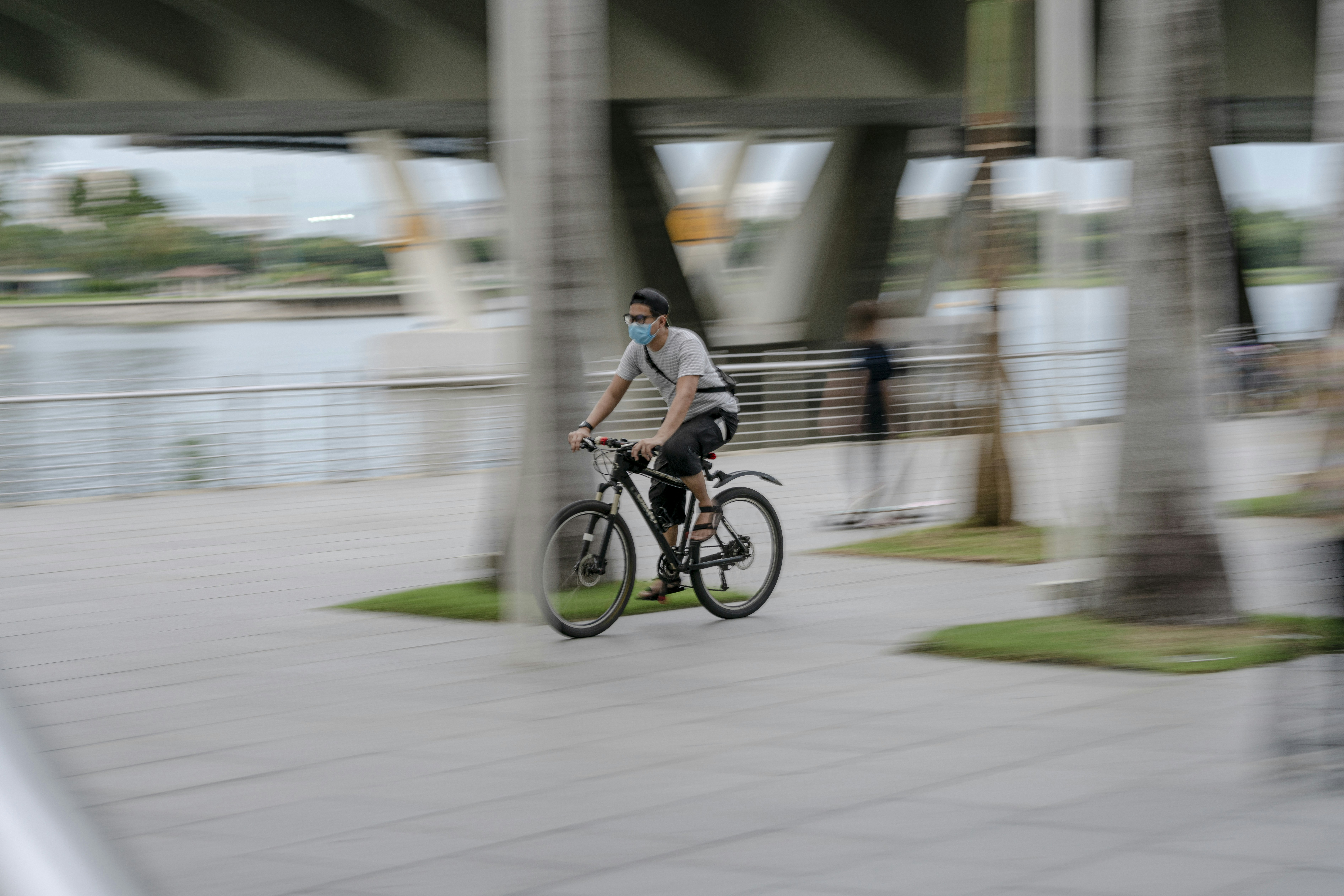 a man riding a bike down a sidewalk next to palm trees