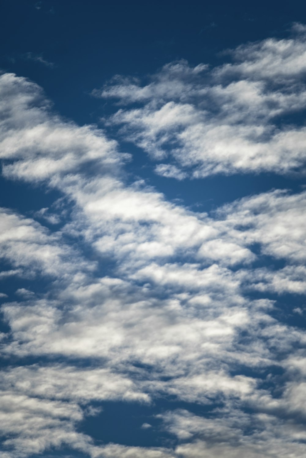 a plane flying through a cloudy blue sky