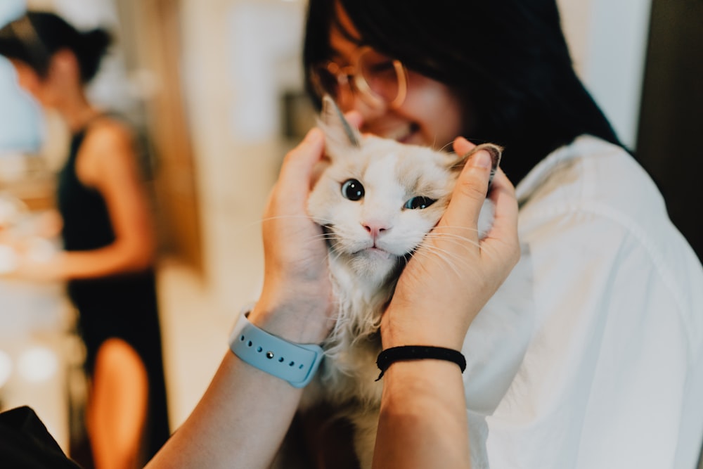 a woman holding a white cat in her hands